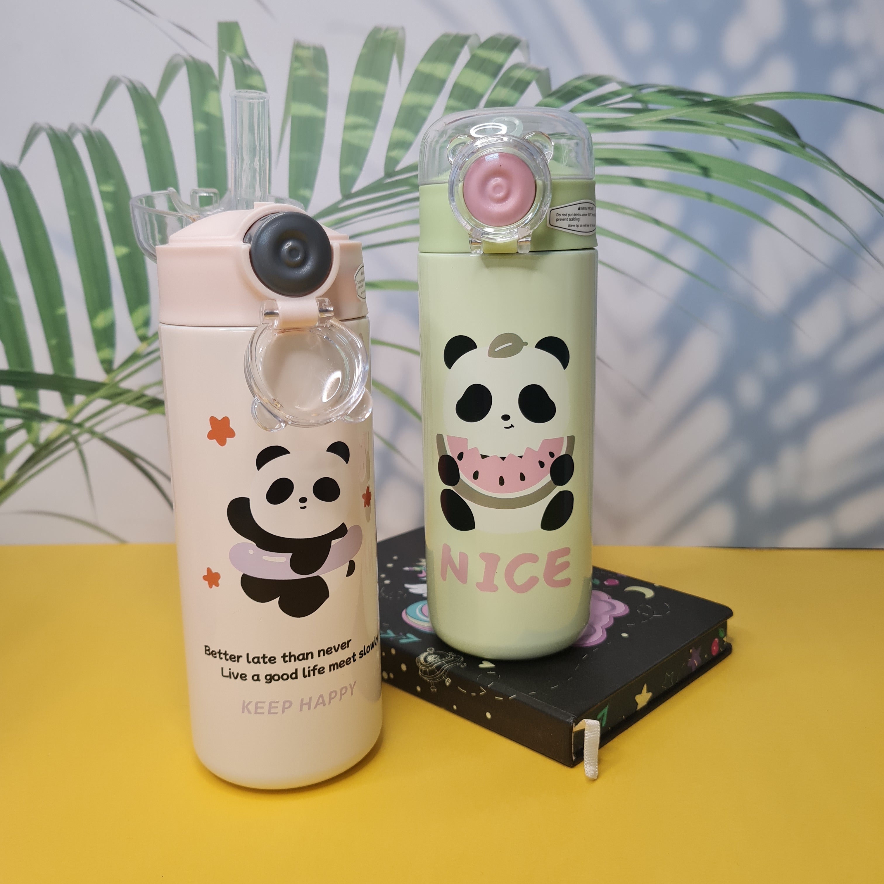 Two panda-themed water bottles on a yellow surface with a leafy background